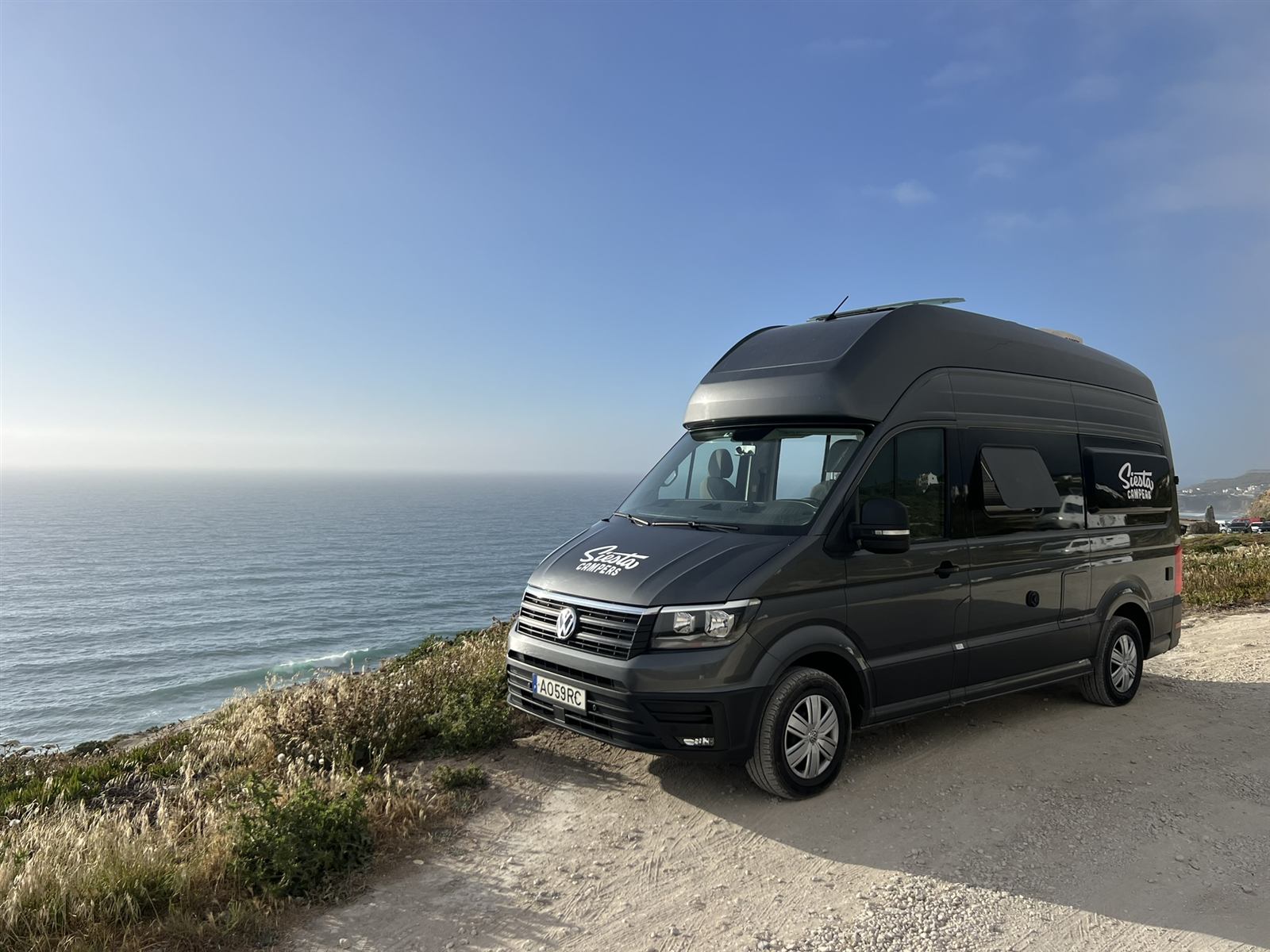 A campervan parked on a cliff above the Atlantic Ocean in Portugal.