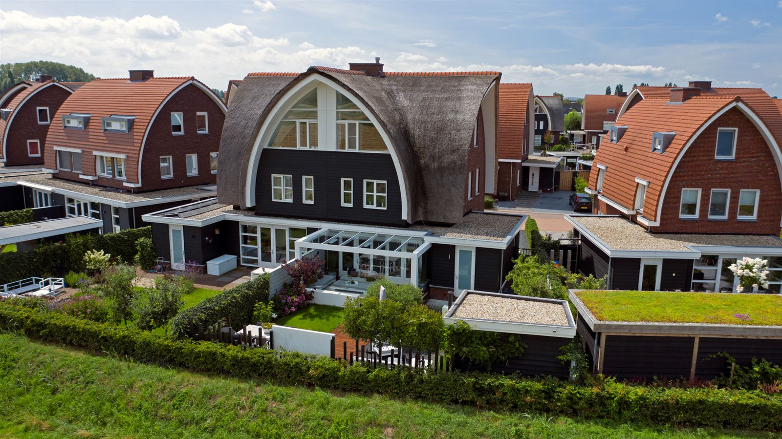 Aerial view of Mwata's former house in the Netherlands, with a curved thatched roof and a garden.